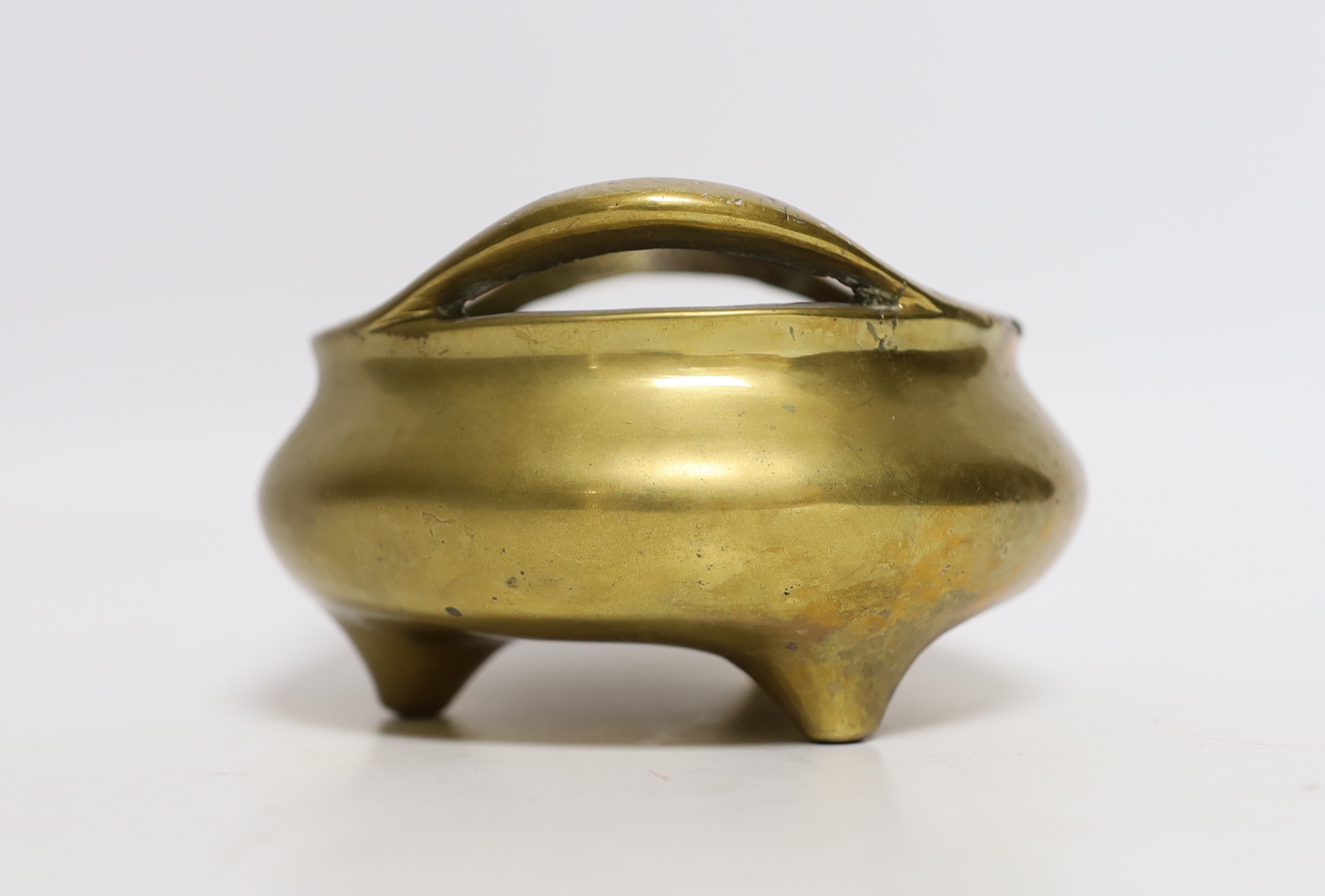 A Chinese bronze tripod censer with twin handles, mark to the base, 14cm wide